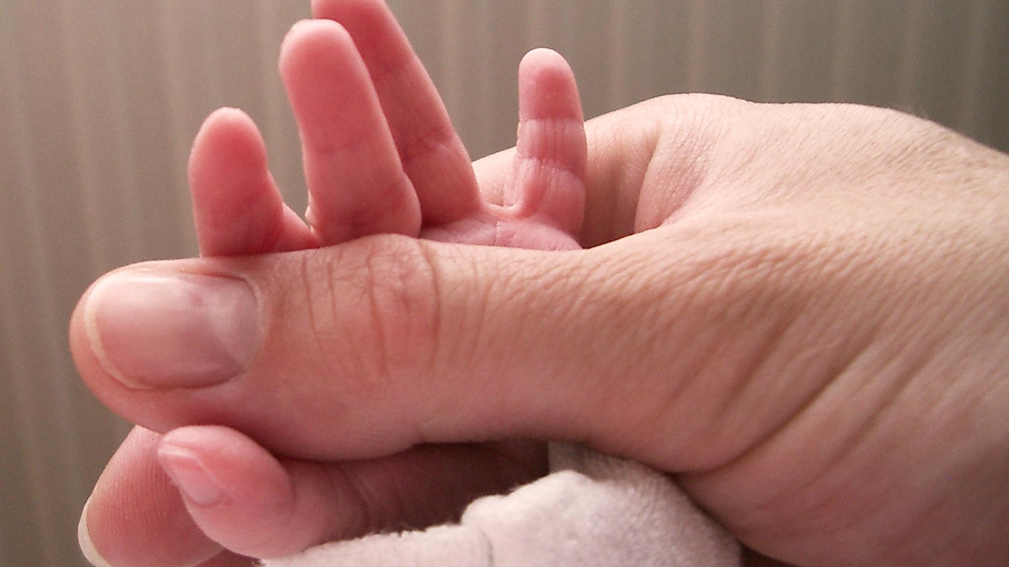 Mutter hält Babyhände fest